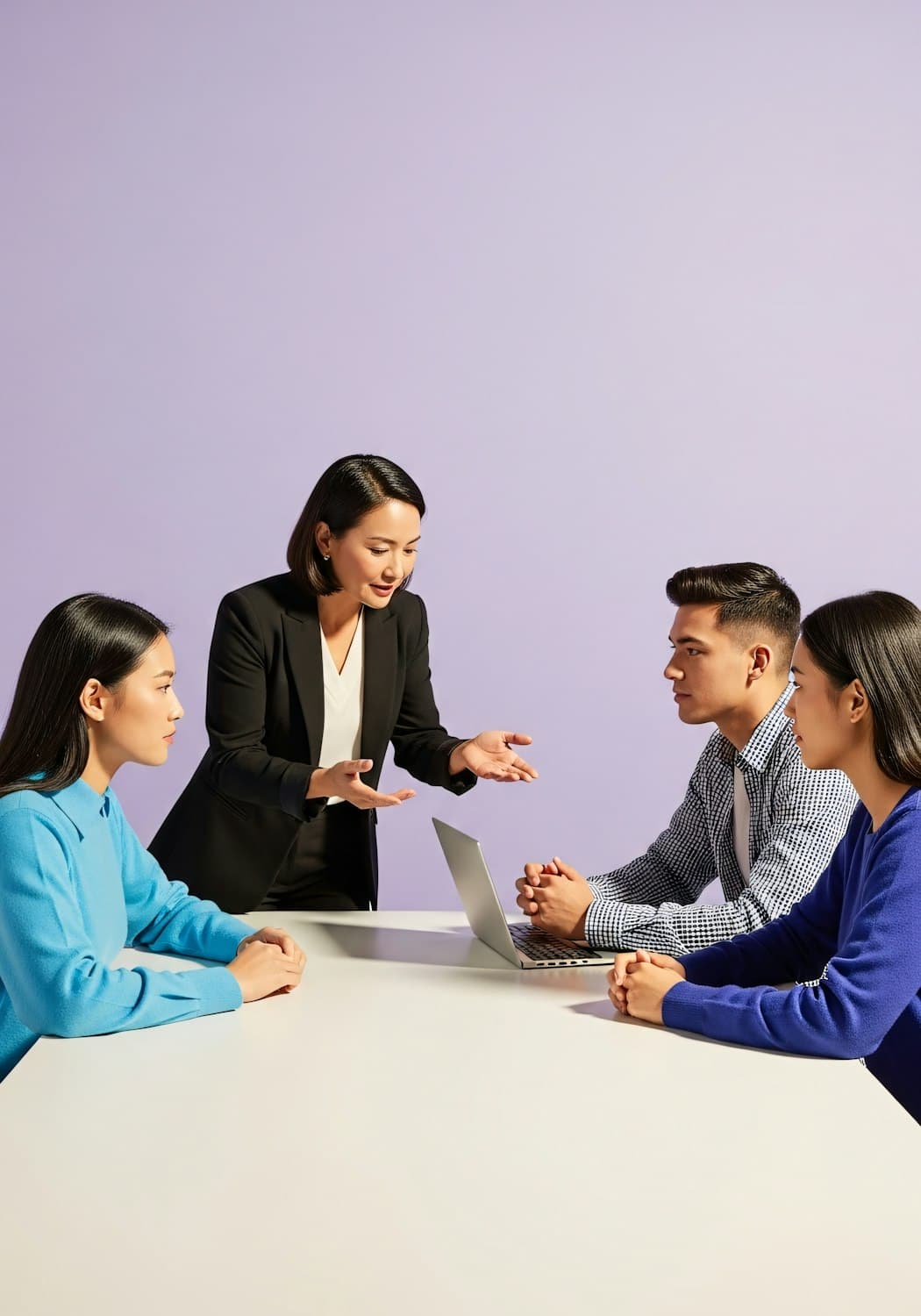 A woman leading a team discussion around a laptop
